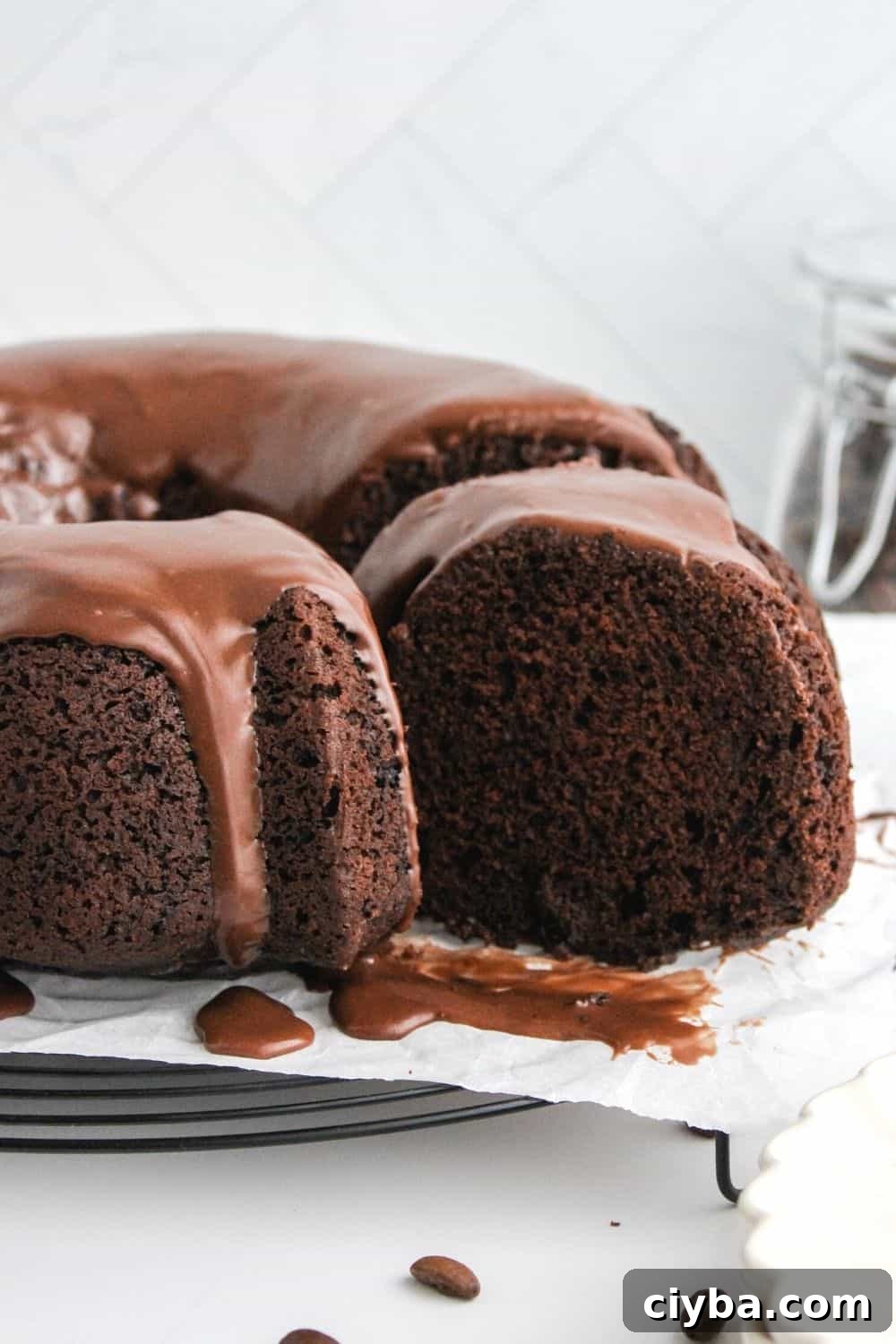 How to Make a Decadent Chocolate Fudge Cake 3 chocolate fudge bundt cake with a slice pulled out, showing the moist interior and silky chocolate glaze