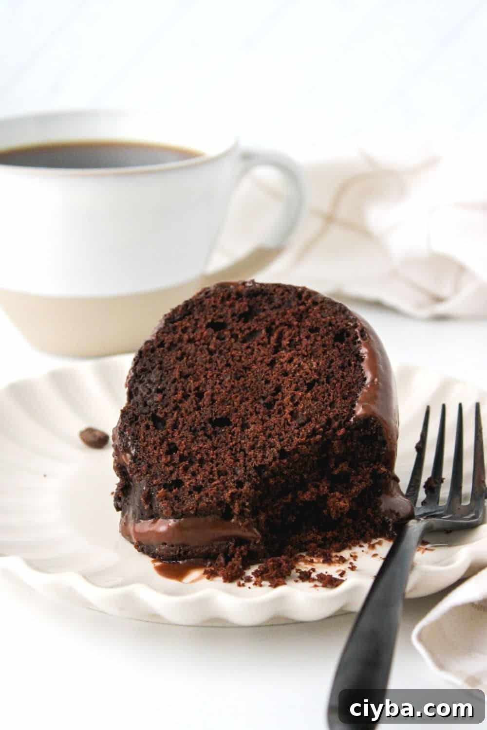 How to Make a Decadent Chocolate Fudge Cake 4 slice of chocolate fudge cake on a white plate, with a cup of coffee in the background