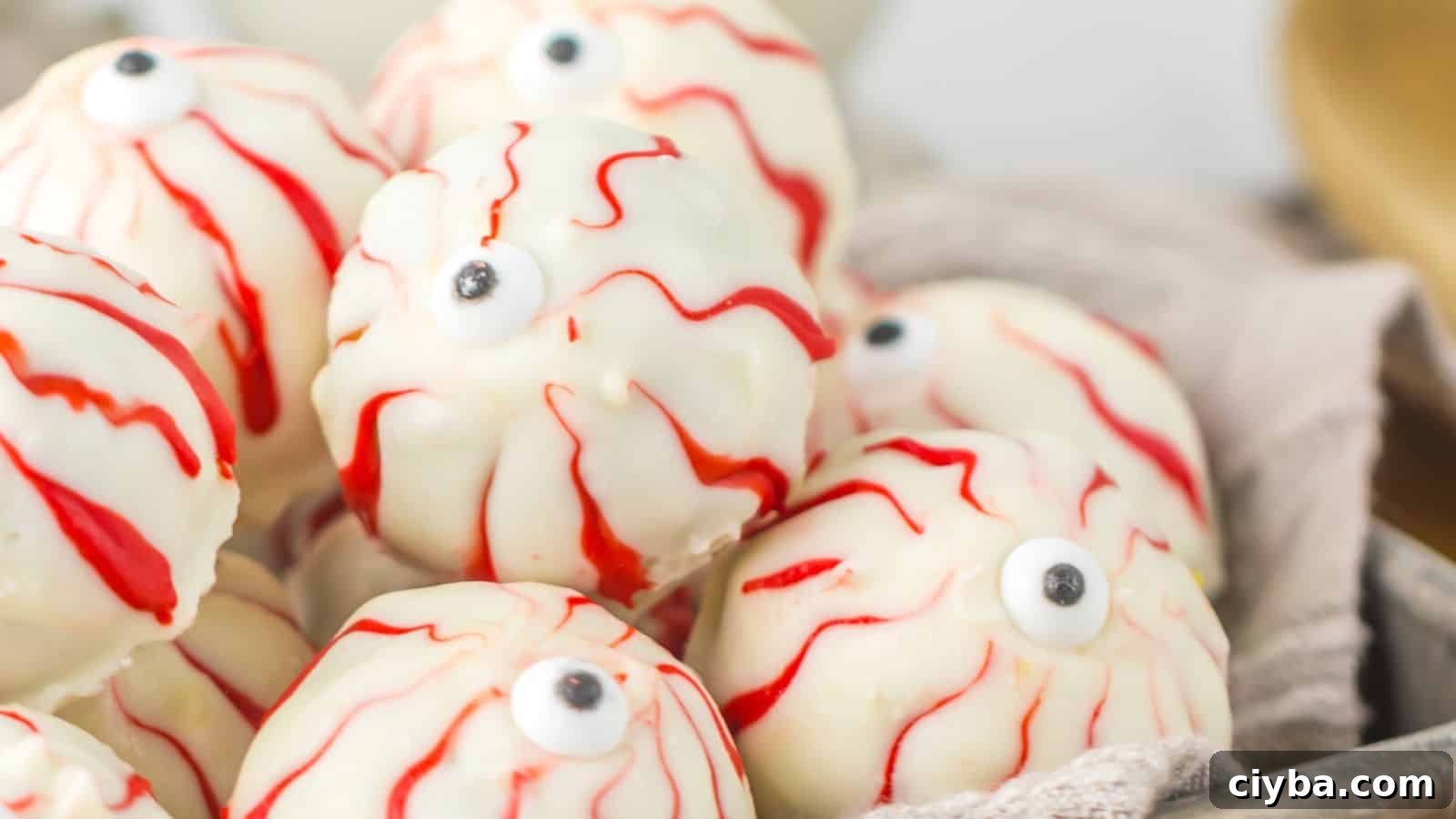 A pile of white chocolate covered truffles decorated to look like spooky Halloween eyeballs, complete with red veins and a candy eyeball in the center.