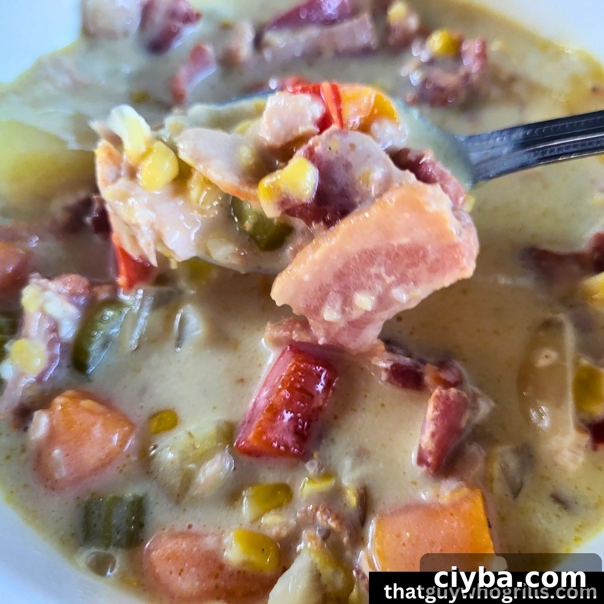 Smoked salmon chowder in a white bowl with a spoon full over the bowl