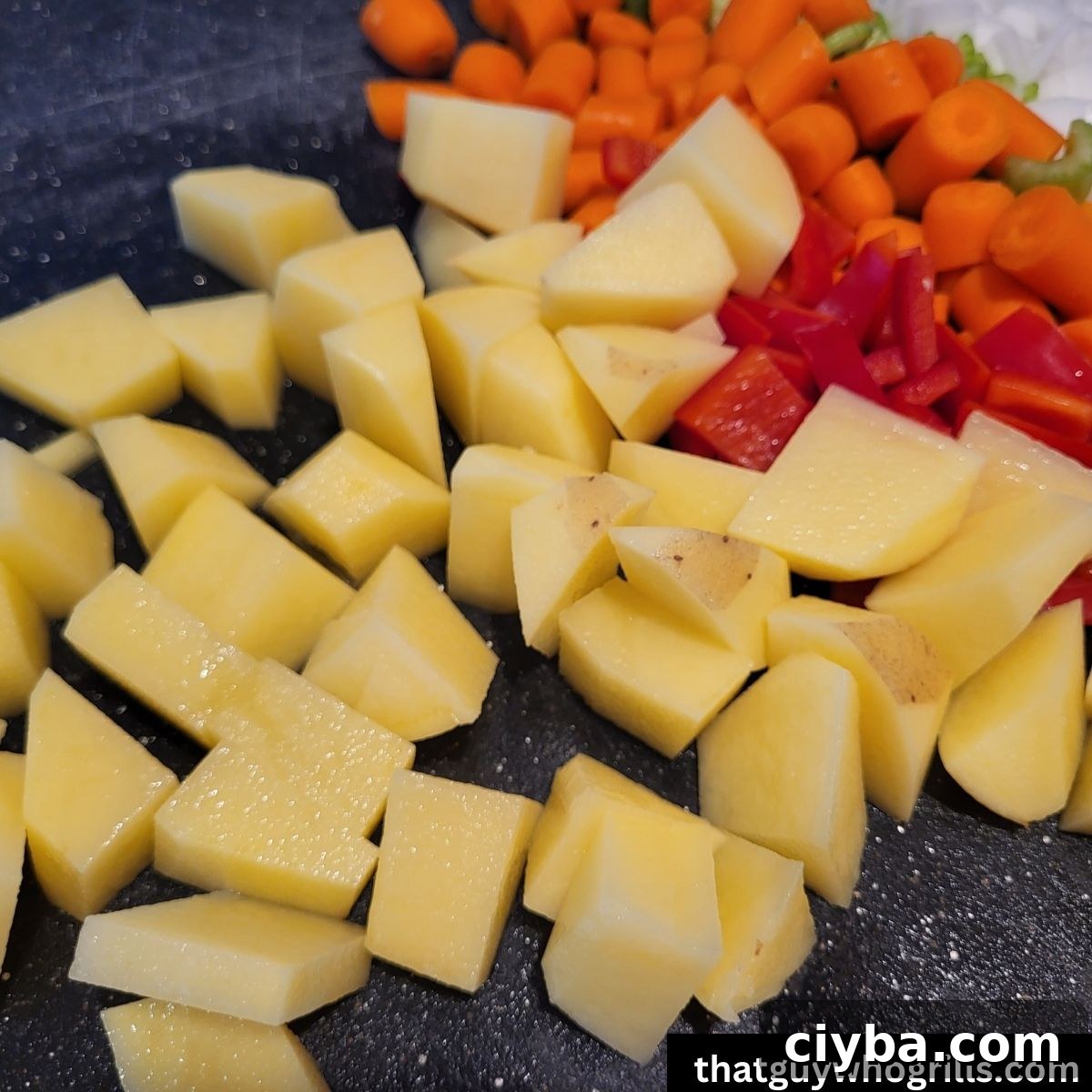 diced gold peppers, carrots, red bell pepeprs, celery and white onions on a black cutting board