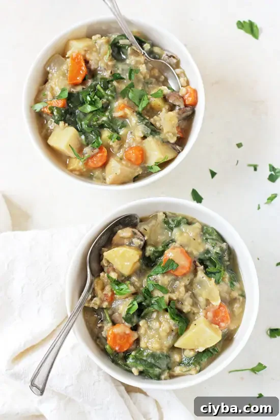 Hearty and comforting, this slow cooker creamy veggie & wild rice soup is like a hug in a bowl! And it’s healthy too! Overhead view of two bowls of Vegetarian Wild Rice Soup with spoons and a white napkin.