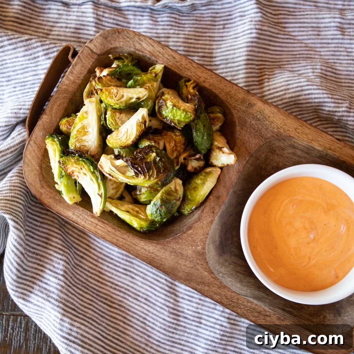 Crispy Air Fryer Brussels Sprouts with Buffalo Ranch Sauce 6 Crispy Brussels sprouts in a wooden bowl with a ramekin of Buffalo-Ranch dipping sauce.