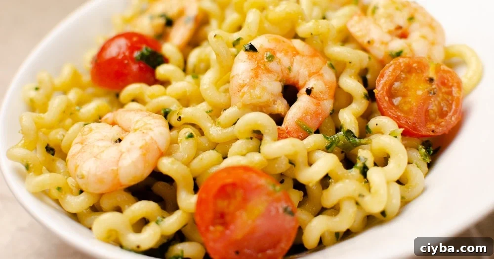 Pesto King Prawn Pasta served in a white bowl, with tomatoes
