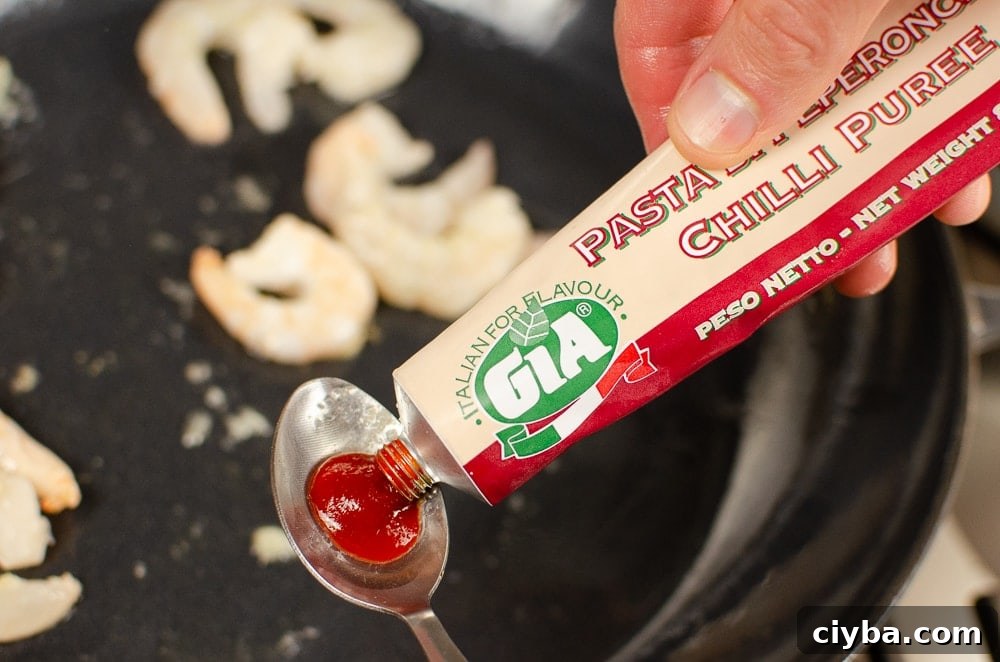Gia Chilli puree being squeezed into a teaspoon to go into a dish with king prawns cooking 