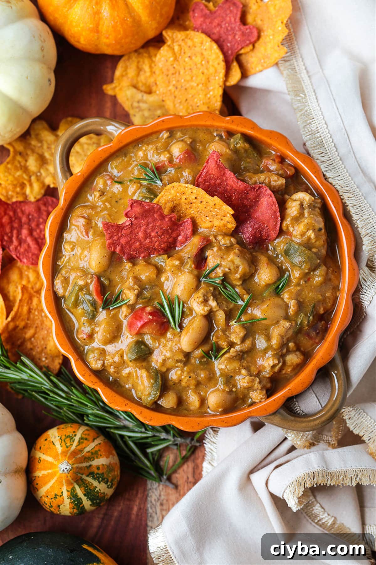 Turkey chili in an orange bowl with pumpkin around