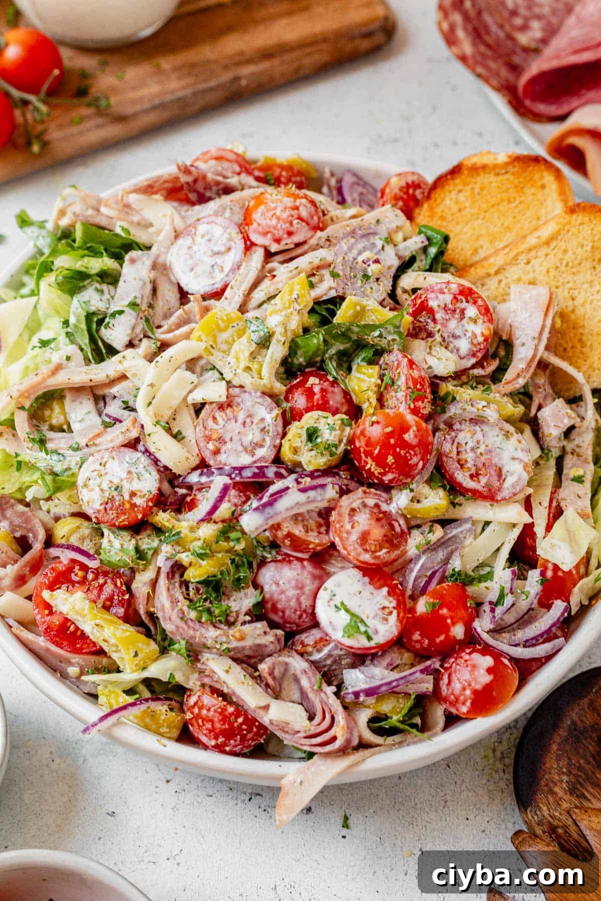 Italian Grinder Salad with Salami, Provolone & Vinaigrette 2 grinder salad in a bowl with a toasted hoagie