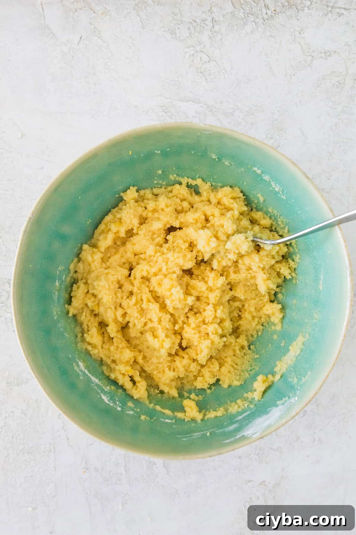 A bowl with a dough that has been mixed in it with a spoon in it.