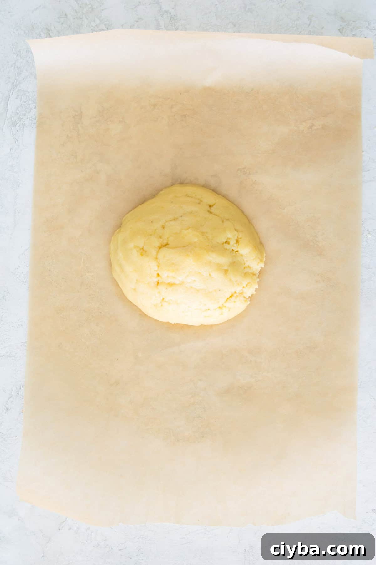 A ball of pastry dough on a piece of parchment paper.