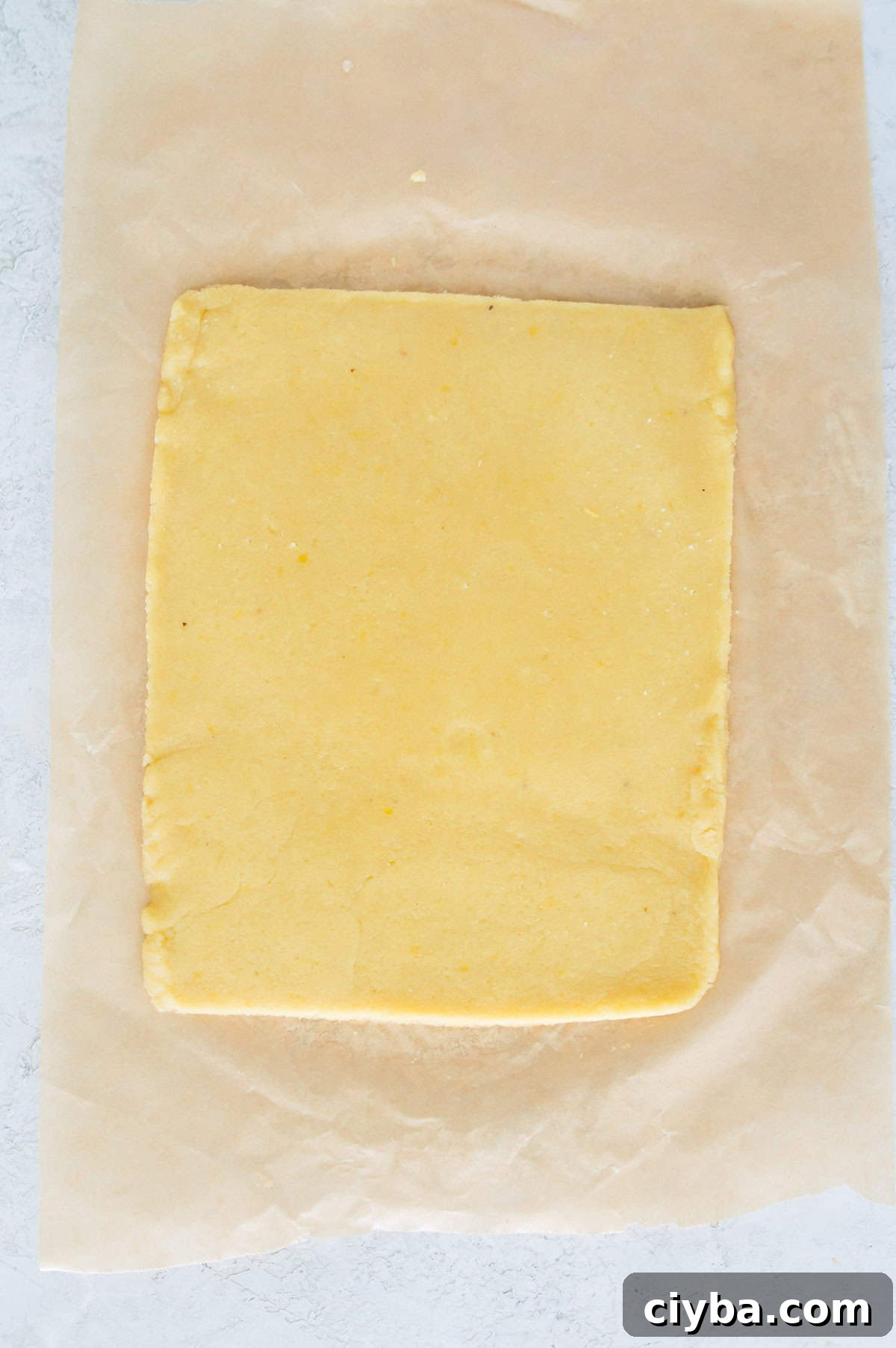 A rectangular piece of dough on piece of parchment paper.