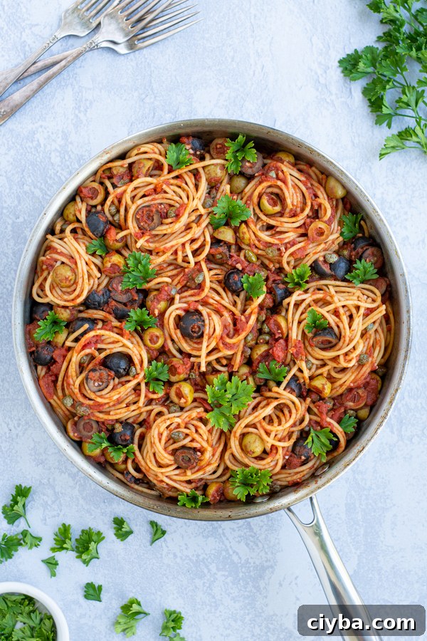 Authentic Spaghetti alla Puttanesca Recipe 5 a large skillet with spaghetti Puttanesca garnished with parsley