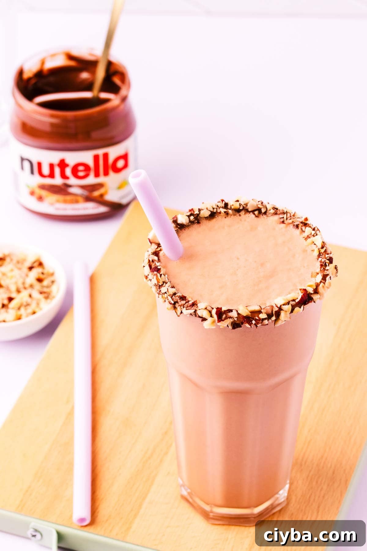 Close up of the top of a milkshake, with Nutella and hazelnuts around the rim of the glass.