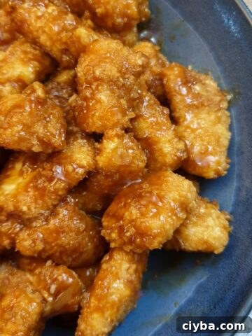 A blue serving dish filled with pieces of sticky orange chicken.