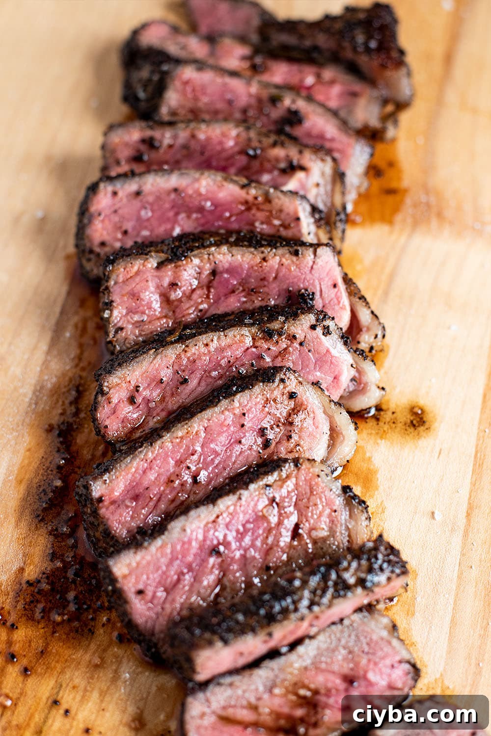 Coffee-Rubbed Steak Recipe for Tender, Flavorful Results 5 A perfect medium rare coffee rubbed NY strip steak sliced into strips and seasoned with flakey sea salt on a wooden cutting board.