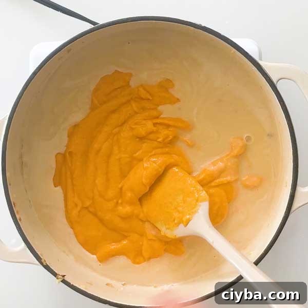 Stirring together roux and cheese sauce in a pot.