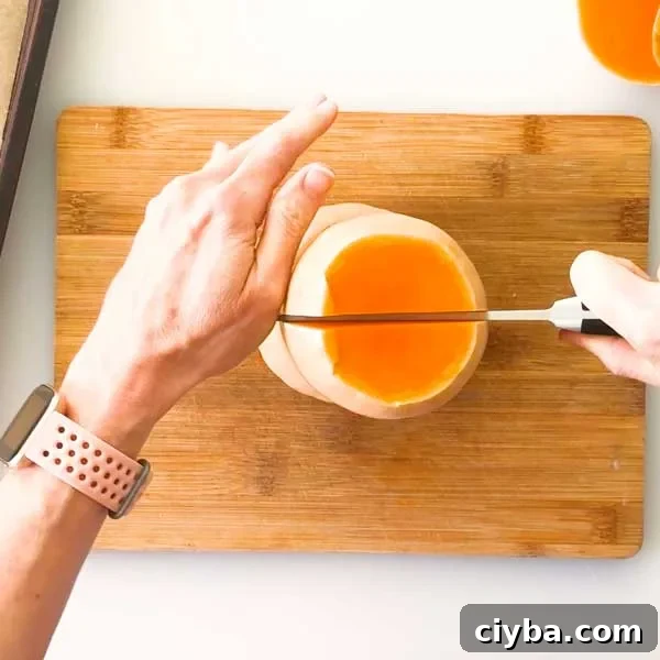 Slicing a butternut squash down the middle with a knife.