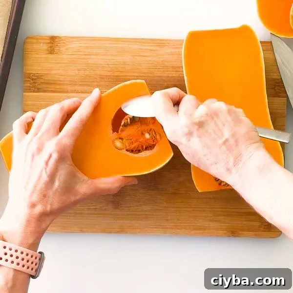 Scooping the seeds out of a butternut squash with a spoon.