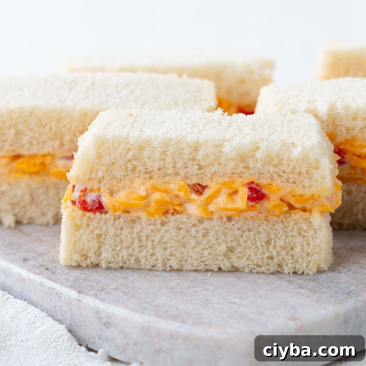 pimento cheese in between two slices of white sandwich bread, cut into thin slices.