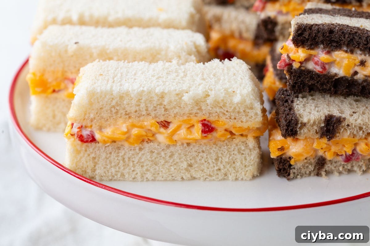 pimento cheese sandwiches on white bread and marble rye bread on a decorative platter.
