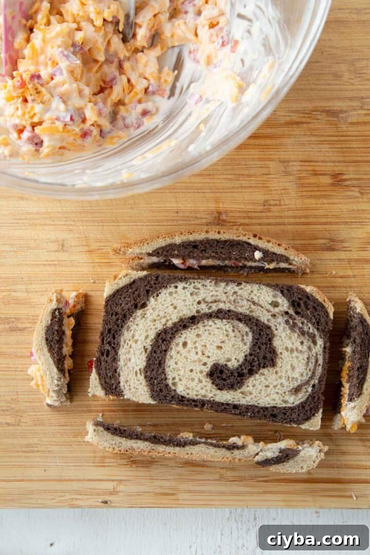 a slice of marble rye with pimento cheese inside and the crusts cut off the bread.