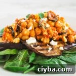 A side view of a plate with spinach topped with grilled eggplant and chickpea salad.